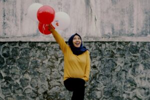 woman in yellow long sleeve shirt holding red balloon